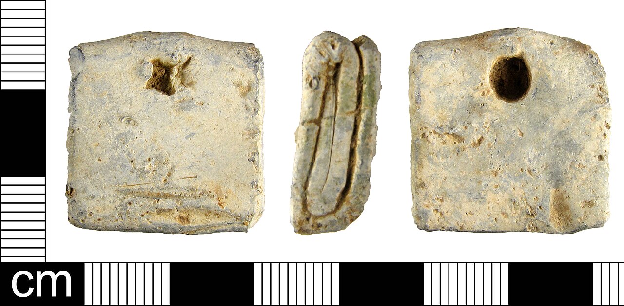 Tábua de maldição romana de chumbo (defixio) exposta em museu