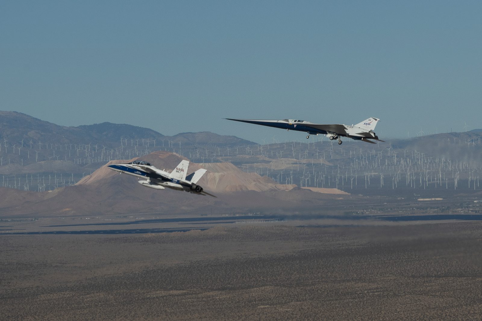 Avião experimental X-59 da NASA em voo, com um caça F-15 ao fundo